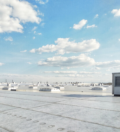 Expansive white rooftop under a blue sky with fluffy clouds